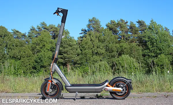 Xiaomi Electric Scooter 6 Max parkerad längs väg i sommarsolen med skogsdunge i bakgrunden