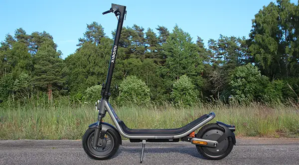 Xiaomi Electric Scooter 6 parkerad i solen på landsväg med skogsbryn i bakgrunden